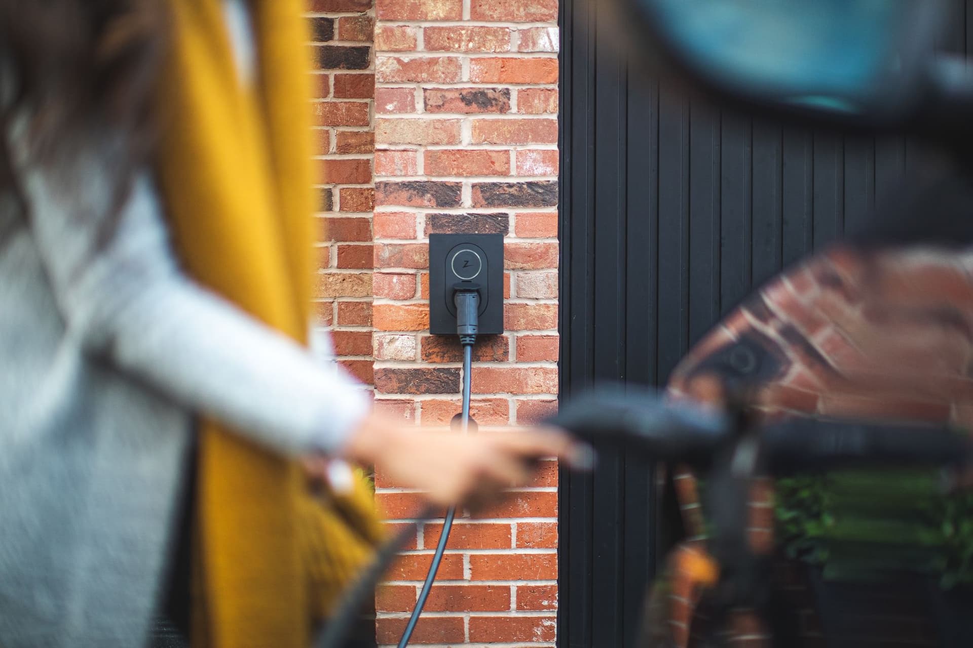 Woman charging an EV with at-home charger in the background