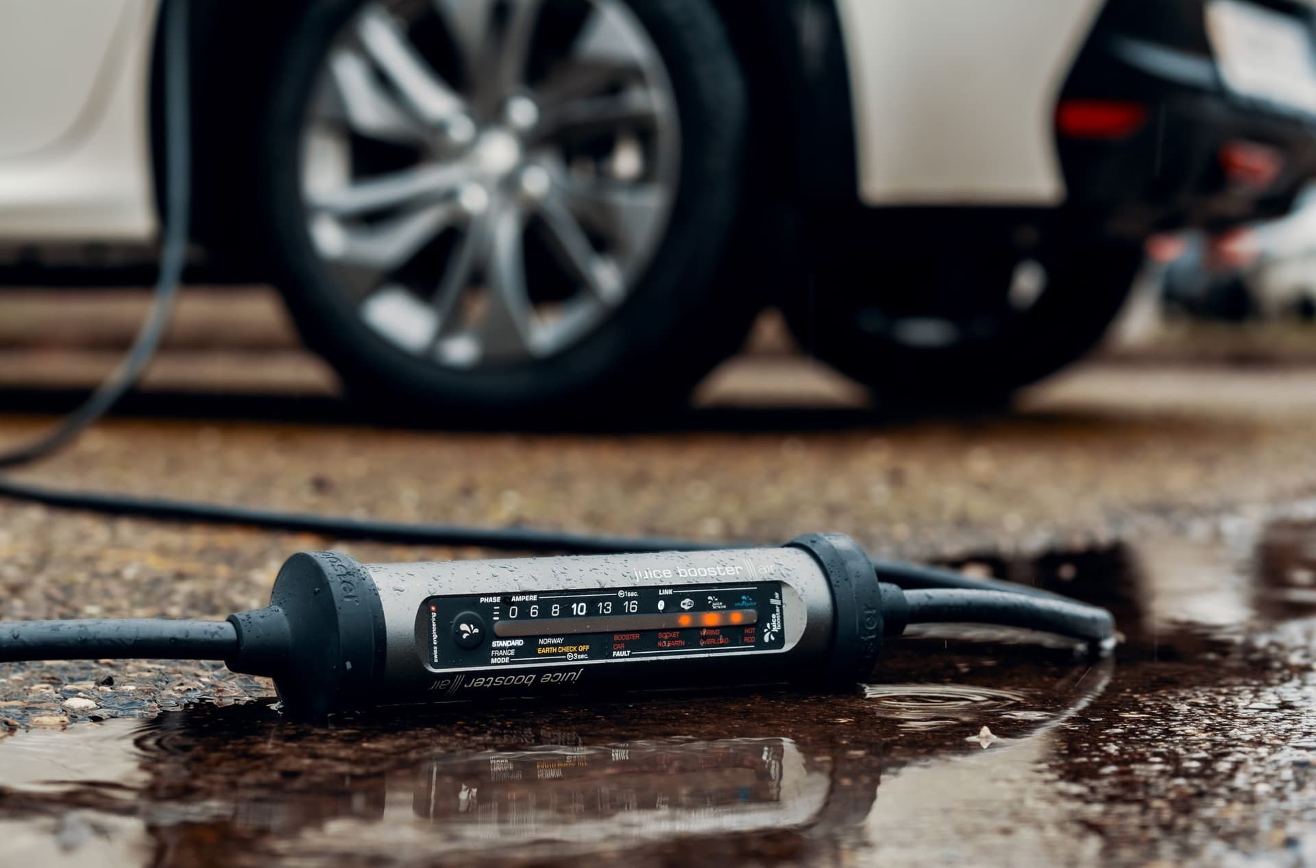 EV charger on the wet ground with EV charging in background