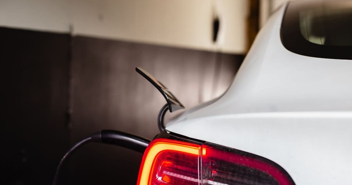 White Tesla parked and charging in a garage