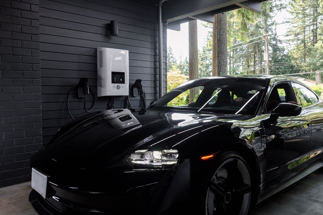 Black electric vehicle in garage with an EV charger in the background